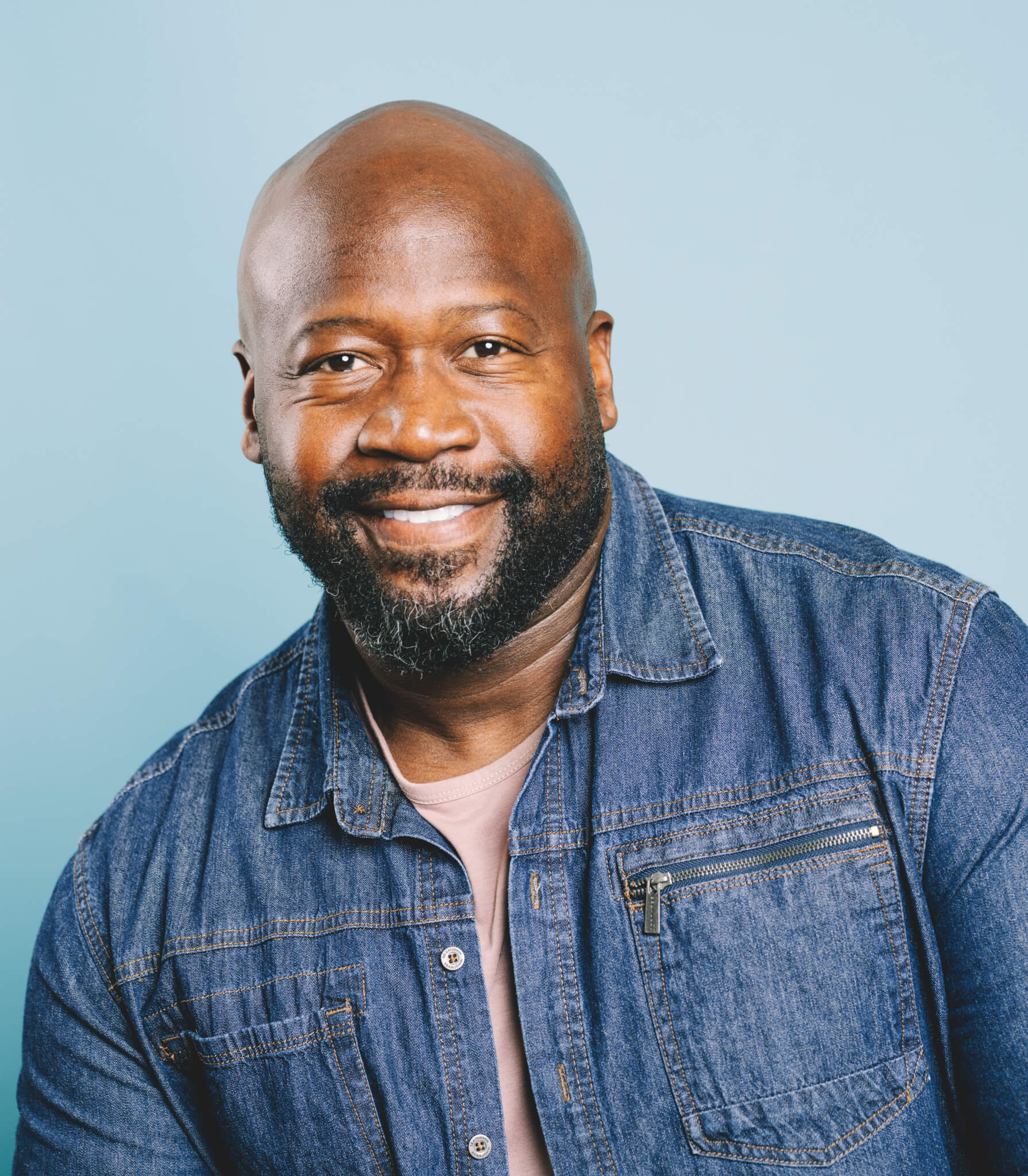 Man in a Denim Shirt In Front of a Light Blue Background